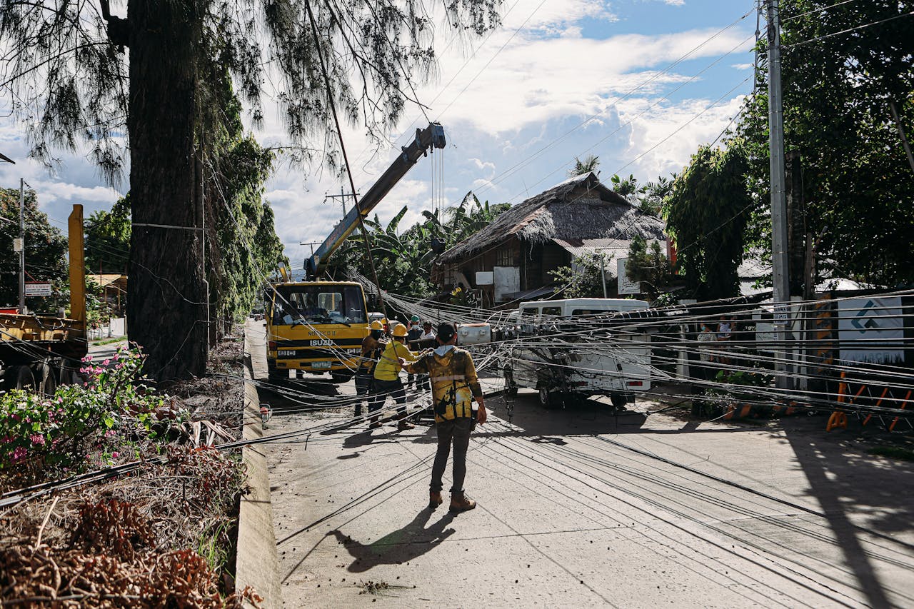 our-story Utility workers fixing downed power lines in a tropical area after a storm. Essential infrastructure maintenance.